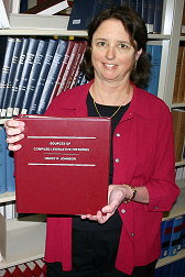 Nancy Johnson holding a bound copy of Sources of Compiled Legislative History
